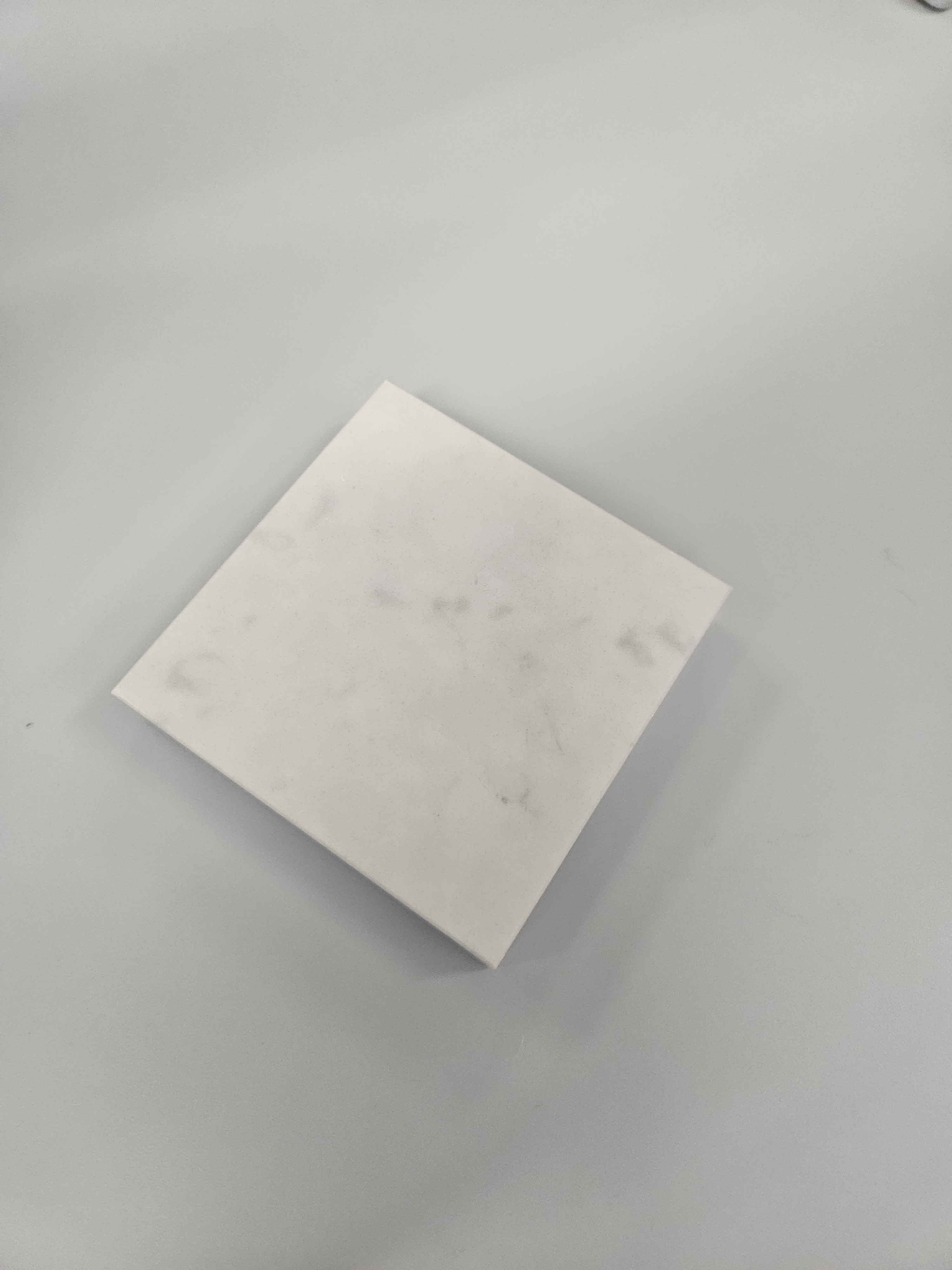 This object is a ceramic block. It is a creamy beige tile that is very smooth on all sides in a shape of a square. It is a refined object but not pliable. This is commonly used for decoration, construction process and to create household items to consume food or holding items 